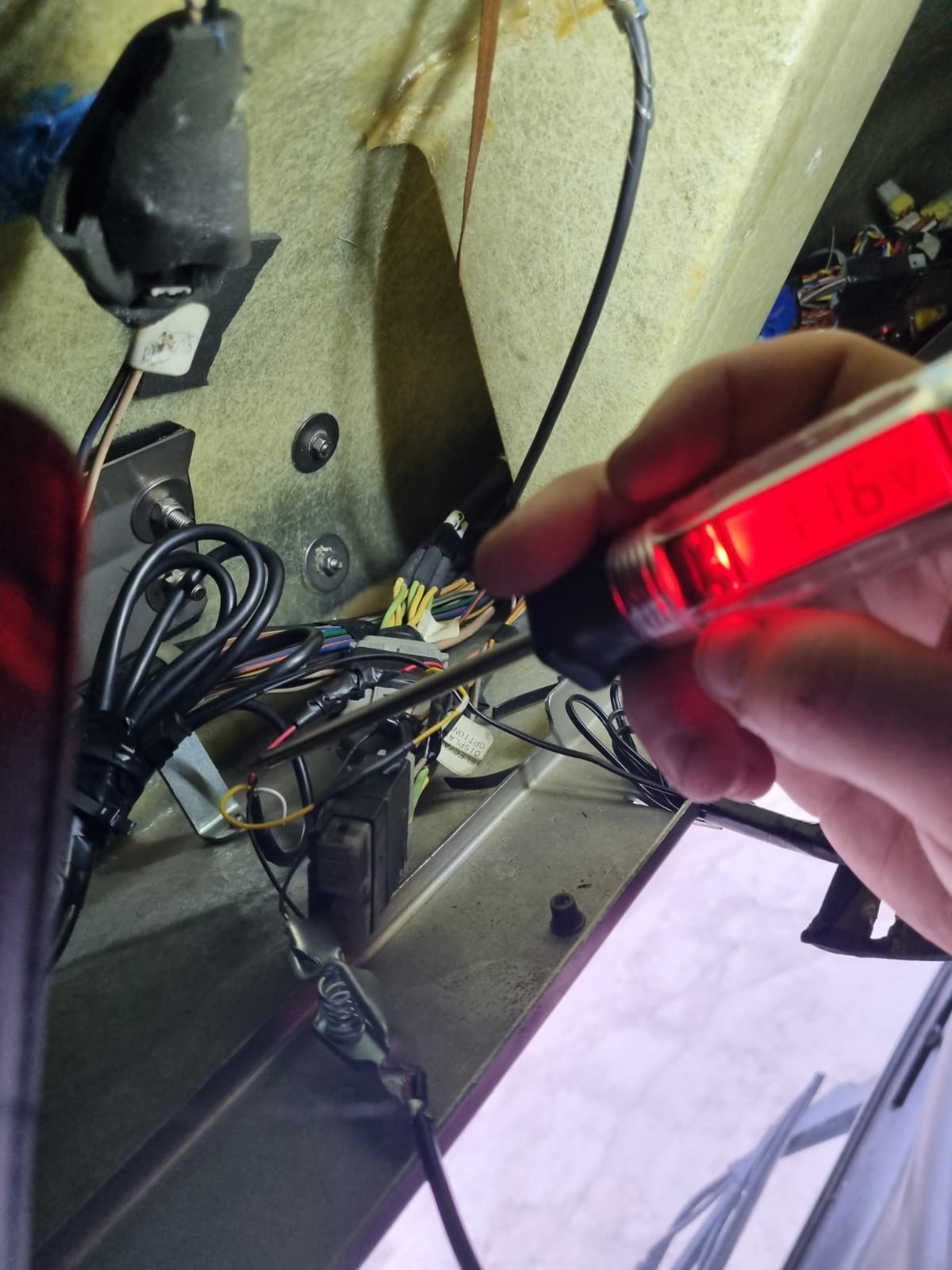 Auto electrician testing vehicle wiring with a multimeter